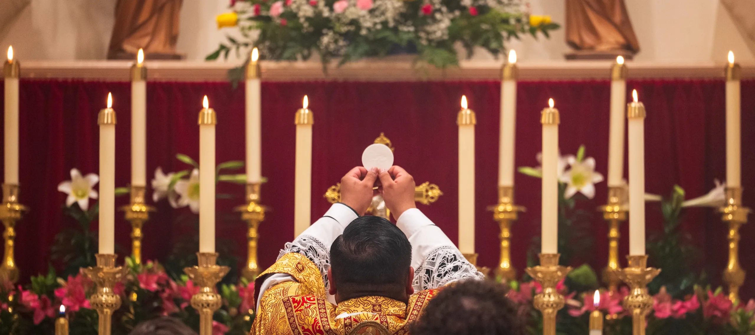 the priest elevating the Host at the altar